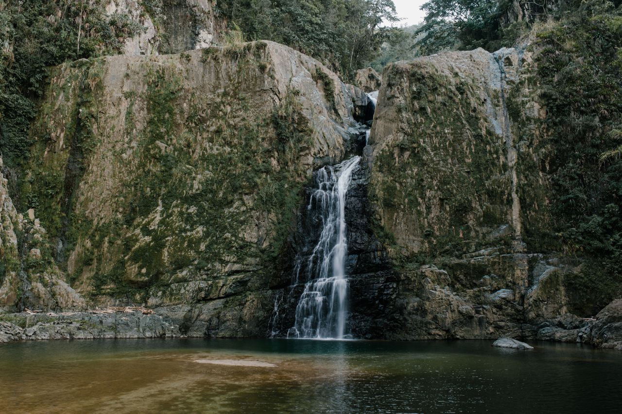 Mastering the First Impression: Your intriguing post title goes here Picturesque view of rapid cascade between cliffs with trees near pond on summer day